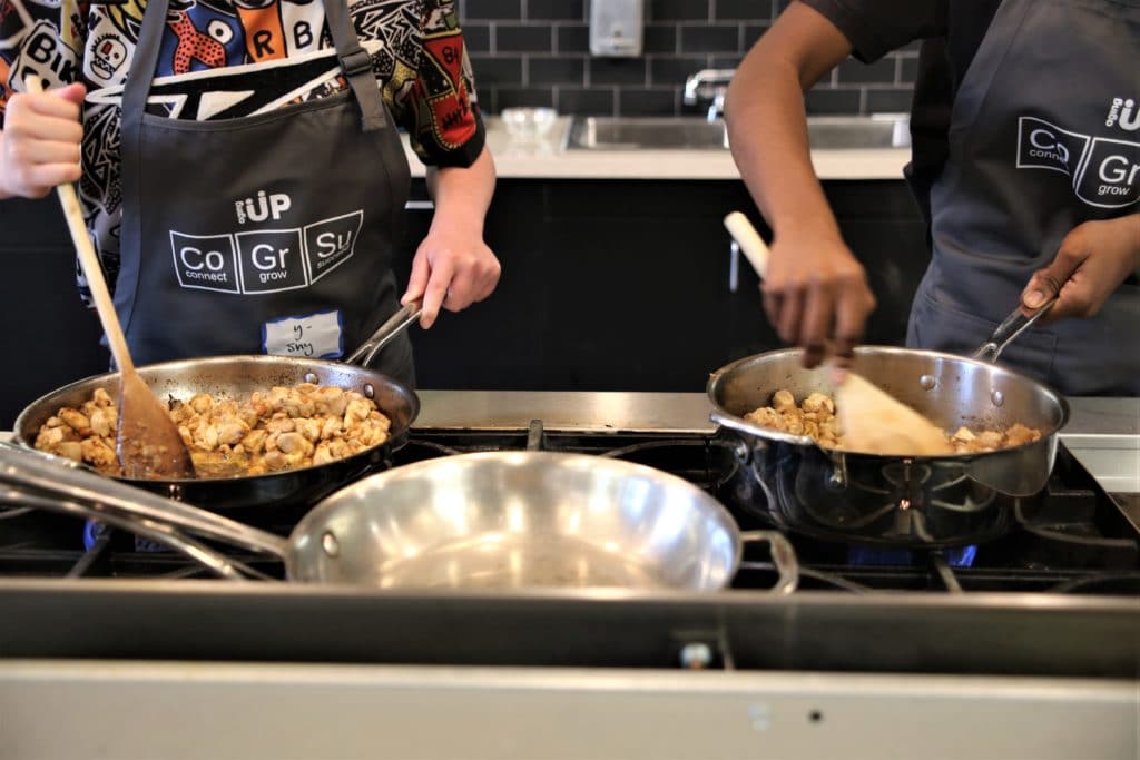 Two teens cooking on stove