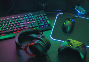 Keyboard, gaming headset, mouse, and controller under the glow of neon light.
