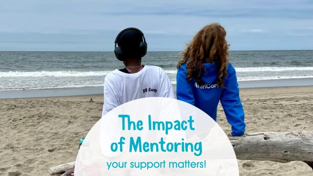 Mentee and adult sitting on a log on the beach