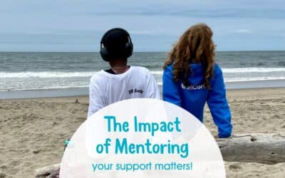 Mentee and adult sitting on a log on the beach